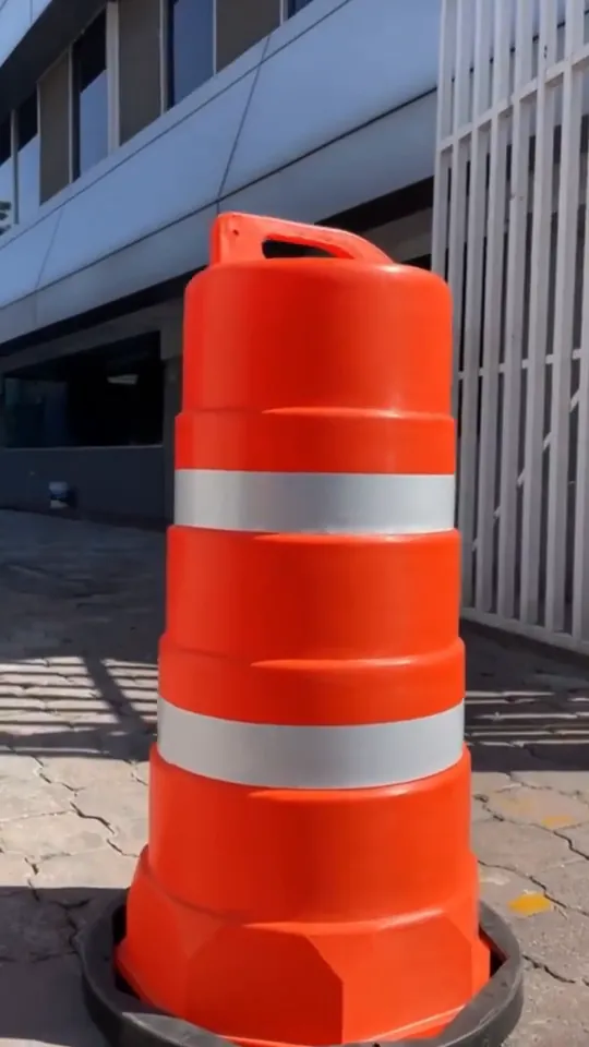 Trafitambo Shark naranja con dos reflejantes sobre su base negra, puesto en la banqueta frente a un edificio